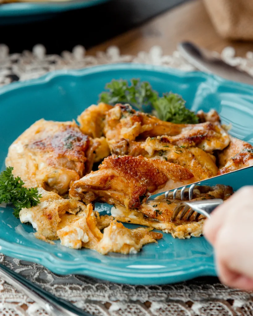 Leftover rotisserie chicken served on a blue plate with herbs and melted cheese