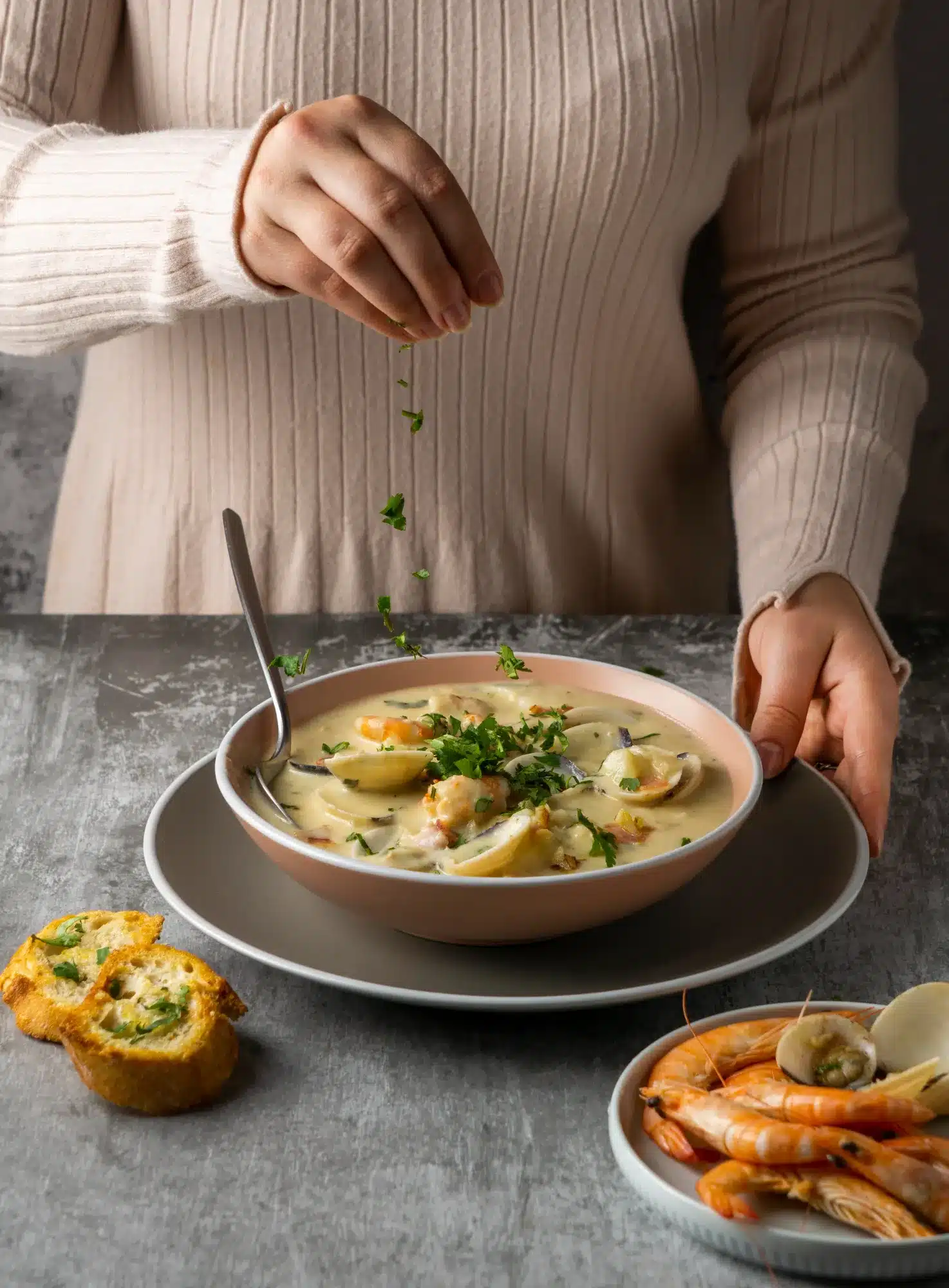 Freshly garnished langostino sauce with parsley, served alongside garlic bread, clams, and shrimp for a delightful seafood meal.