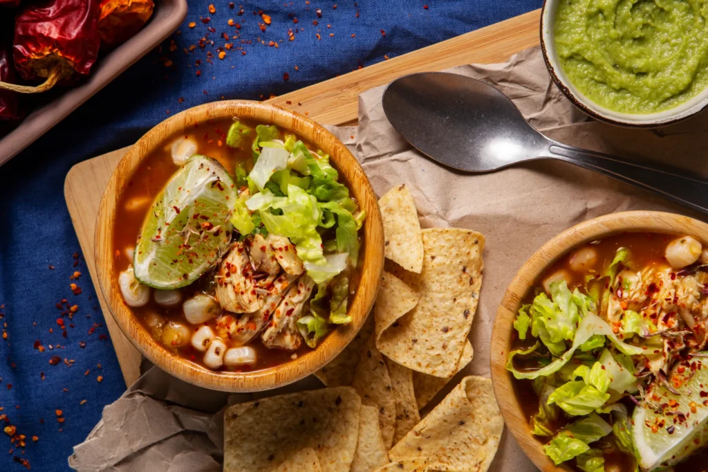 A vibrant bowl of Taco Soup Frios served with lime, lettuce, and tortilla chips, showcasing fresh ingredients and chilled taco flavors.