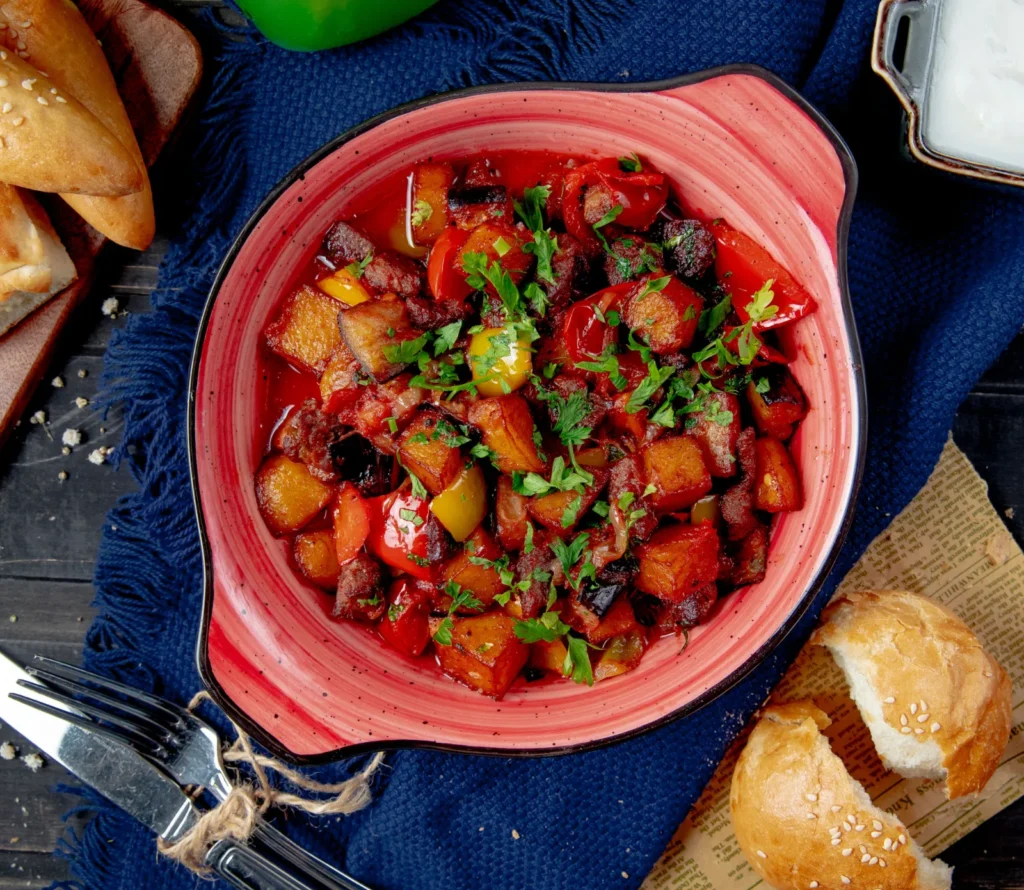 Colorful bowl of canned corned beef breakfast recipe with bell peppers, garnished with parsley, served on a rustic table with bread and a green drink.