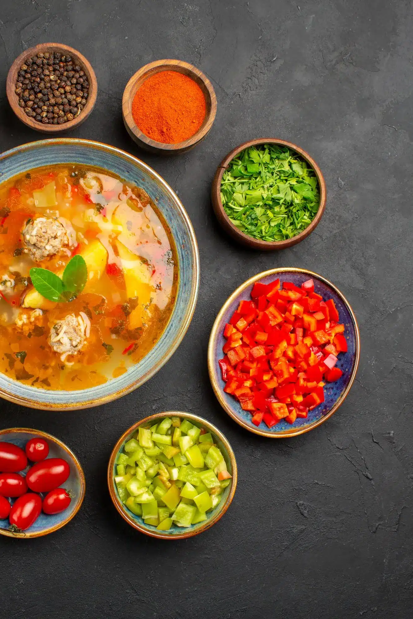 A bowl of Taco Soup Frios Recipe surrounded by fresh ingredients like diced bell peppers, cherry tomatoes, and spices, ready for preparation.