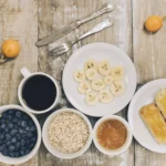 Gluten-free dairy-free breakfast with banana slices, blueberries, oats, jam, and toast on a rustic wooden table