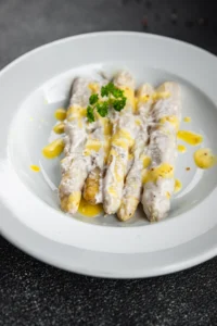 White asparagus in a creamy sauce, garnished with fresh parsley, highlighting a classic German recipe.