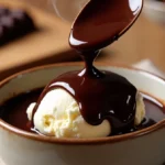Rich Black Label Chocolate Sauce being poured from a spoon onto vanilla ice cream in a rustic bowl, with steam rising and chocolate in the background.