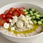 Greek salad overnight oats in a white bowl with fresh veggies and feta
