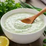 Creamy green goddess dressing in bowl with fresh herbs