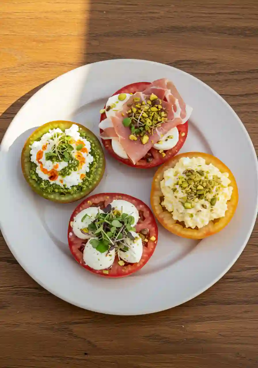 Tomato slices with gourmet toppings arranged on a platter for serving