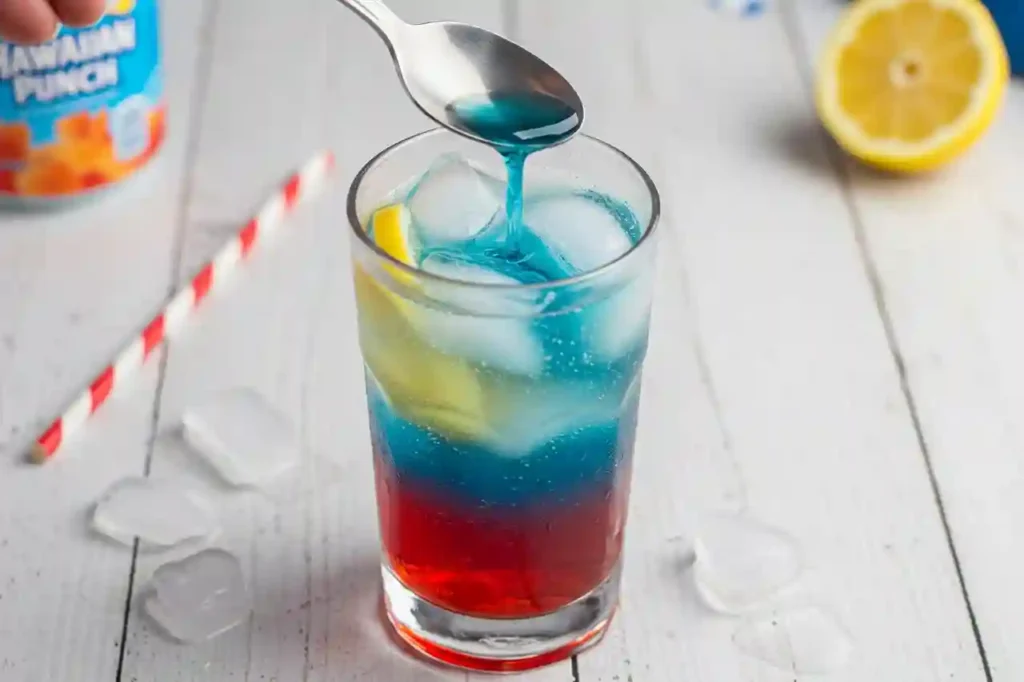 Pouring blue Hawaiian Punch over spoon into patriotic slushy mocktail