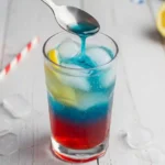 Pouring blue Hawaiian Punch over spoon into patriotic slushy mocktail