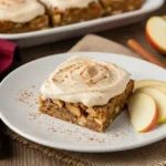 Chewy apple cinnamon blondies with maple cream cheese frosting on parchment