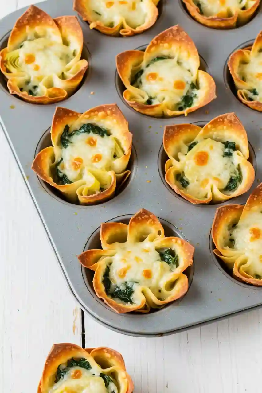 Spinach Artichoke Wonton Cups – Thanksgiving Appetizers Recipes Baked spinach artichoke wonton cups with melted cheese in a muffin tin, a festive bite for Thanksgiving appetizers recipes.