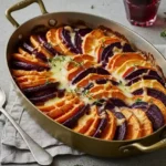 Root vegetable gratin baked in a brass-handled dish with golden cheese topping and thyme